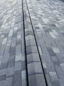 A close-up view of asphalt roof shingles with a ridge vent running along the peak of the roof.